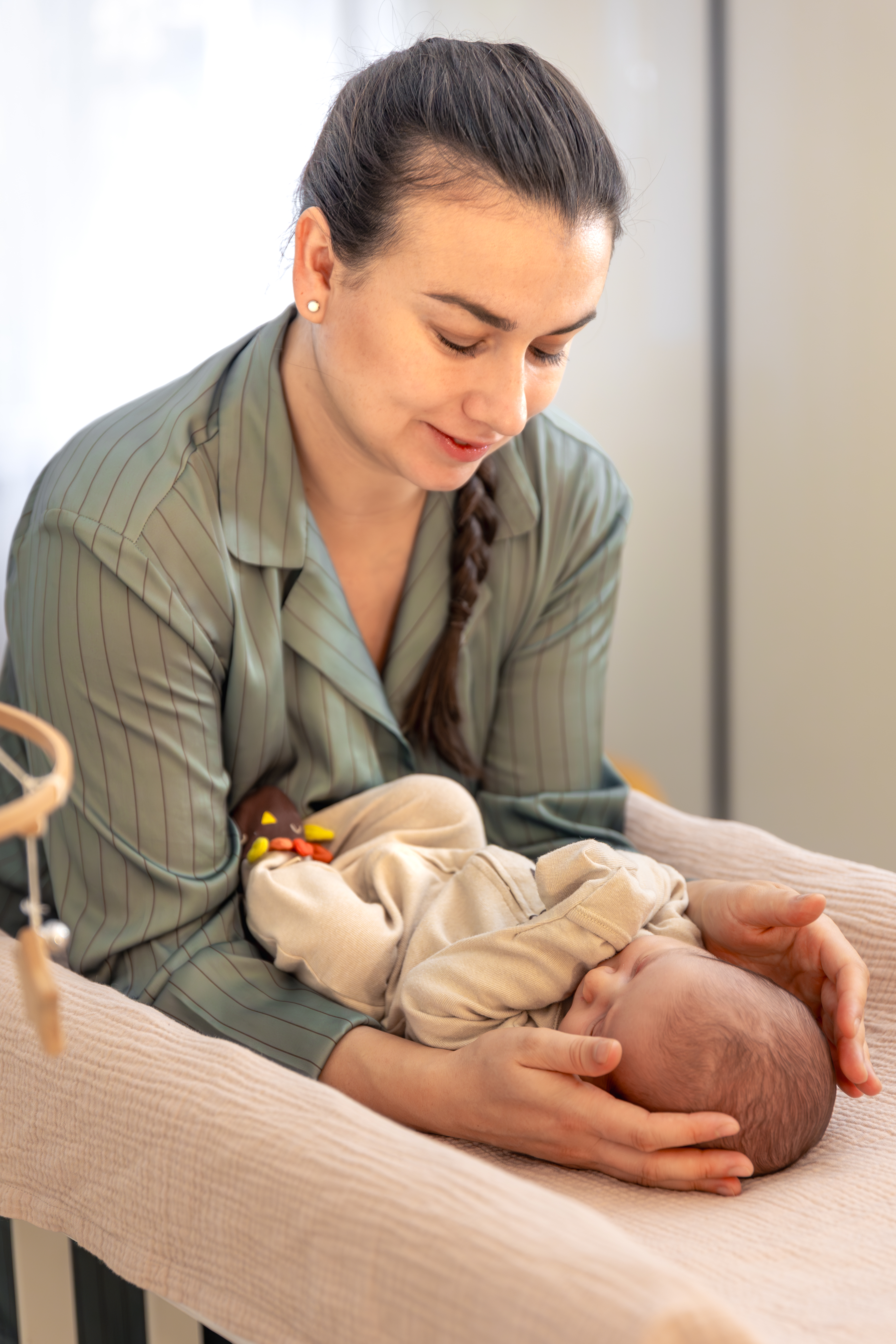 A young mother with a newborn baby. Newborn baby. High quality photo. Lying in bed. Motherhood. Mother with baby at home.